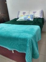 Una cama con colcha color aguamarina y almohadas con diseños florales.