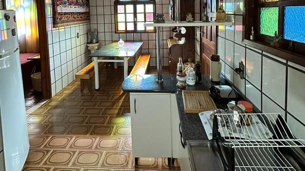 Een keuken met een houten plafond, betegelde muren, een raam met glas-in-lood en een betegelde vloer.