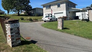 A residential driveway with a house, a white car, and a mailbox marked '153'.