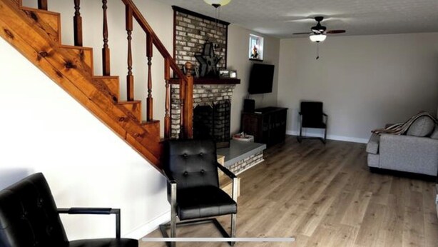 A living room with a wooden staircase, a fireplace, a television, and a sofa.