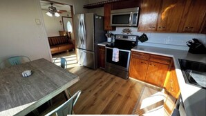 A kitchen with wooden cabinets, a stainless steel refrigerator, a microwave, and a stove.