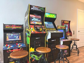 Máquinas de arcade, taburetes de madera y una puerta en una habitación.