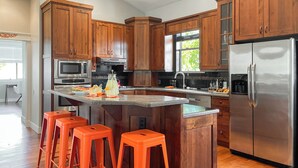 Een moderne keuken met houten kastjes, roestvrijstalen apparatuur en een centraal eiland met barkrukken.