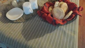 A table set with various items including plates, cups, a thermos, and a basket of bread.