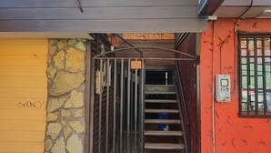 A building with a stone wall, a yellow door, and a staircase leading to an upper level.