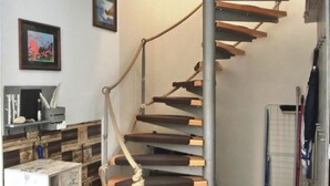 A spiral staircase with wooden steps and metal railings, leading to an upper floor. - Vacation home directly on the dune, approx. 50 m to the Baltic Sea - Markgrafenheide (Rostock)