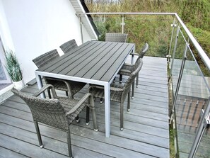 A wooden deck with a table and chairs, surrounded by a metal railing. - Vacation home directly on the dune, approx. 50 m to the Baltic Sea - Markgrafenheide (Rostock)