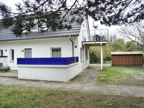 A white building with a blue accent wall, a covered outdoor area, and a small shed. - Vacation home directly on the dune, approx. 50 m to the Baltic Sea - Markgrafenheide (Rostock)
