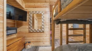 A wooden interior with bunk beds, a flat-screen TV, and a geometric wall decoration.