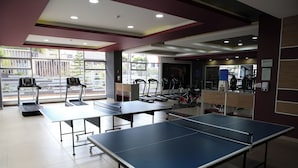 A fitness center with exercise equipment, including treadmills and weight machines, and a ping pong table. - Lujosa Suite Privada: Cama King y Piscina en Lugar Céntrico y Seguro (Quito)