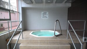 A swimming pool area with steps leading down to the pool, a safety sign on the wall, and metal railings. - Lujosa Suite Privada: Cama King y Piscina en Lugar Céntrico y Seguro (Quito)