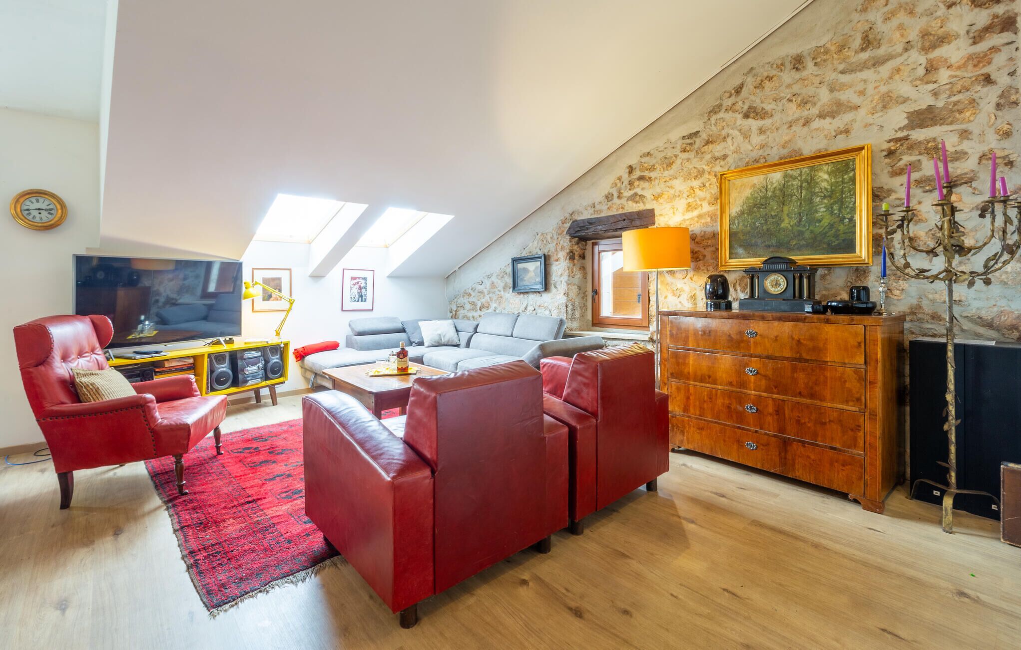 Una sala de estar acogedora con un sofá rojo, un aparador de madera y un cuadro en la pared.