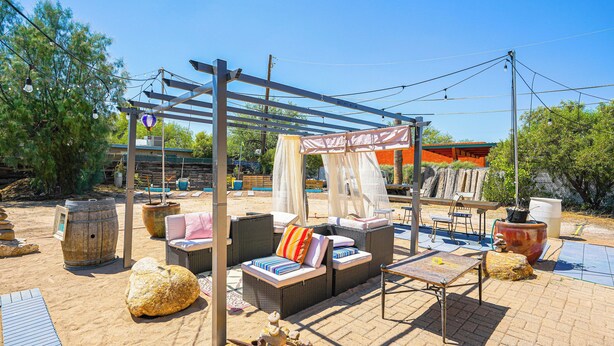 Un espace extérieur aménagé en terrasse, avec des meubles en osier, une pergola et un grand bac à plantes.