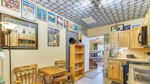 Une cuisine avec des meubles de rangement en bois, une table à manger avec des chaises et divers appareils de cuisine.