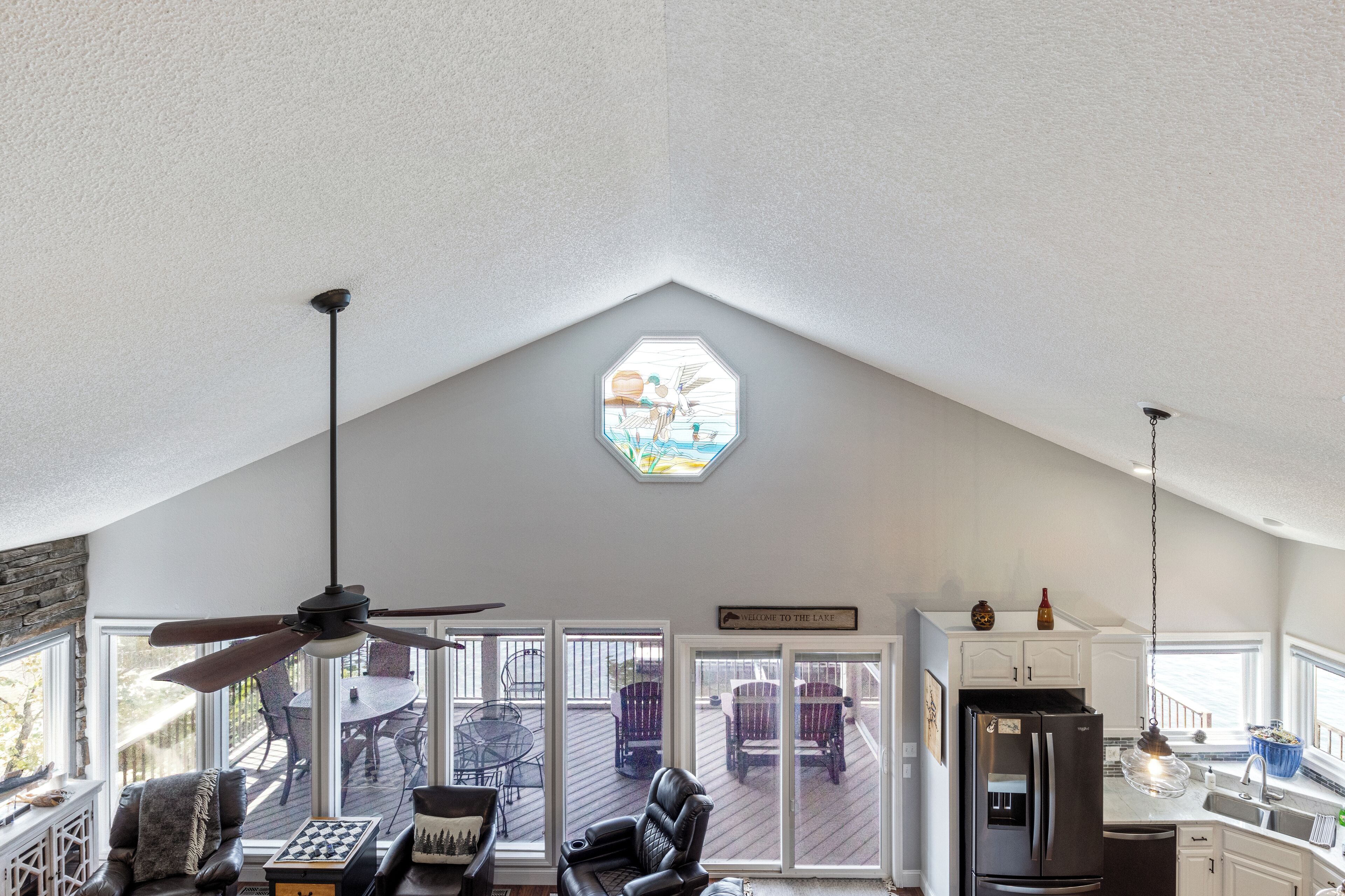 Un vaste espace de vie agrémenté d’un ventilateur de plafond, d’un jeu d’échecs et offrant une vue sur la terrasse grâce à de grandes fenêtres.