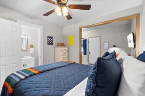 A bedroom with a bed, a dresser, a mirror, and a ceiling fan.