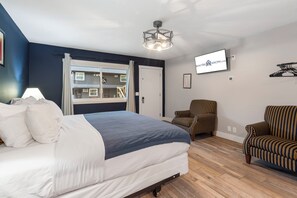 Une chambre à coucher avec un lit, une chaise, une télévision et une fenêtre.