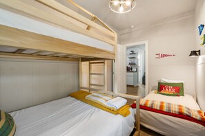 Quarto com beliches, porta para banheiro e um aviso na parede.
