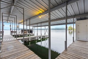 A covered dock area with a view of a calm lake and distant hills.