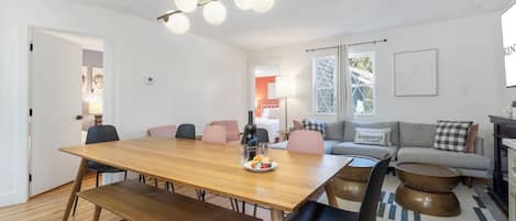 Un salón moderno con una mesa de comedor de madera, sillas negras y un sofá con cojines estampados.