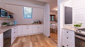 A modern kitchen with white cabinetry, a wooden countertop, and a window providing natural light. - Horseshoe Acres - Home theater, spa room, hot tub (Oak Hill)