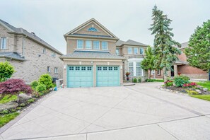 A two-story house with a garage, surrounded by a well-maintained lawn and a driveway.