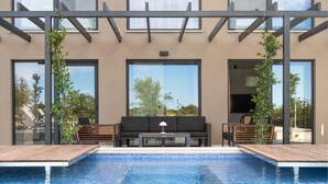 A modern outdoor pool area with a wooden deck, a black sofa, and two wooden chairs. - Stunning home in Bale (Bale)