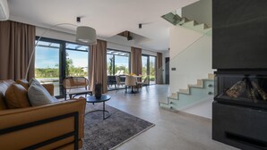 A modern living room with a sofa, a dining table, and a staircase. - Stunning home in Bale (Bale)