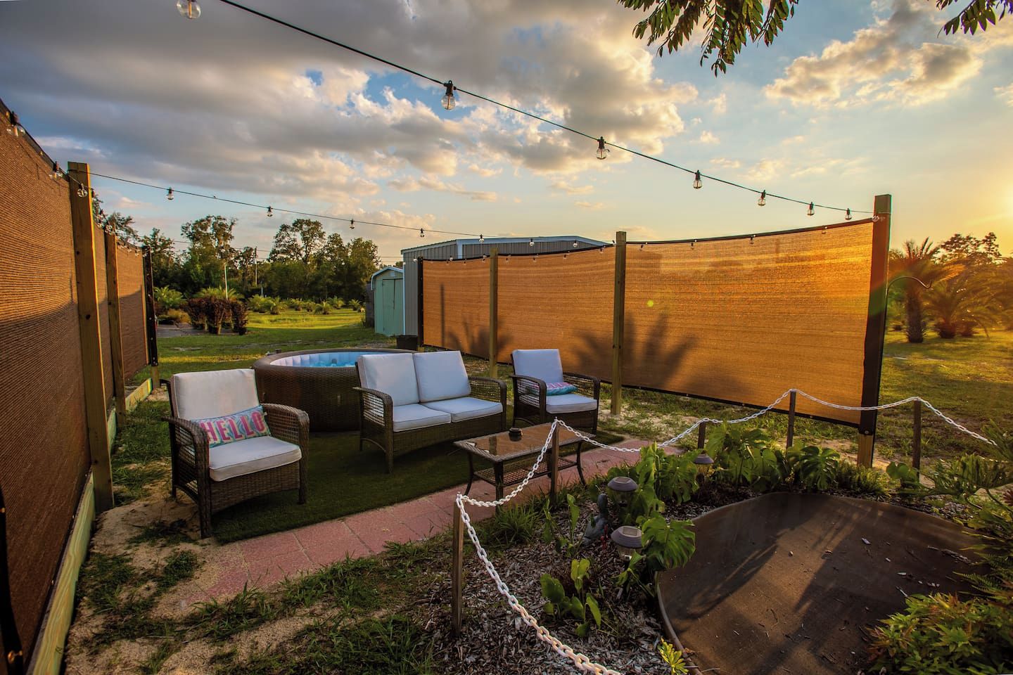 An outdoor seating area with wicker furniture, a small table, and a covered hot tub.