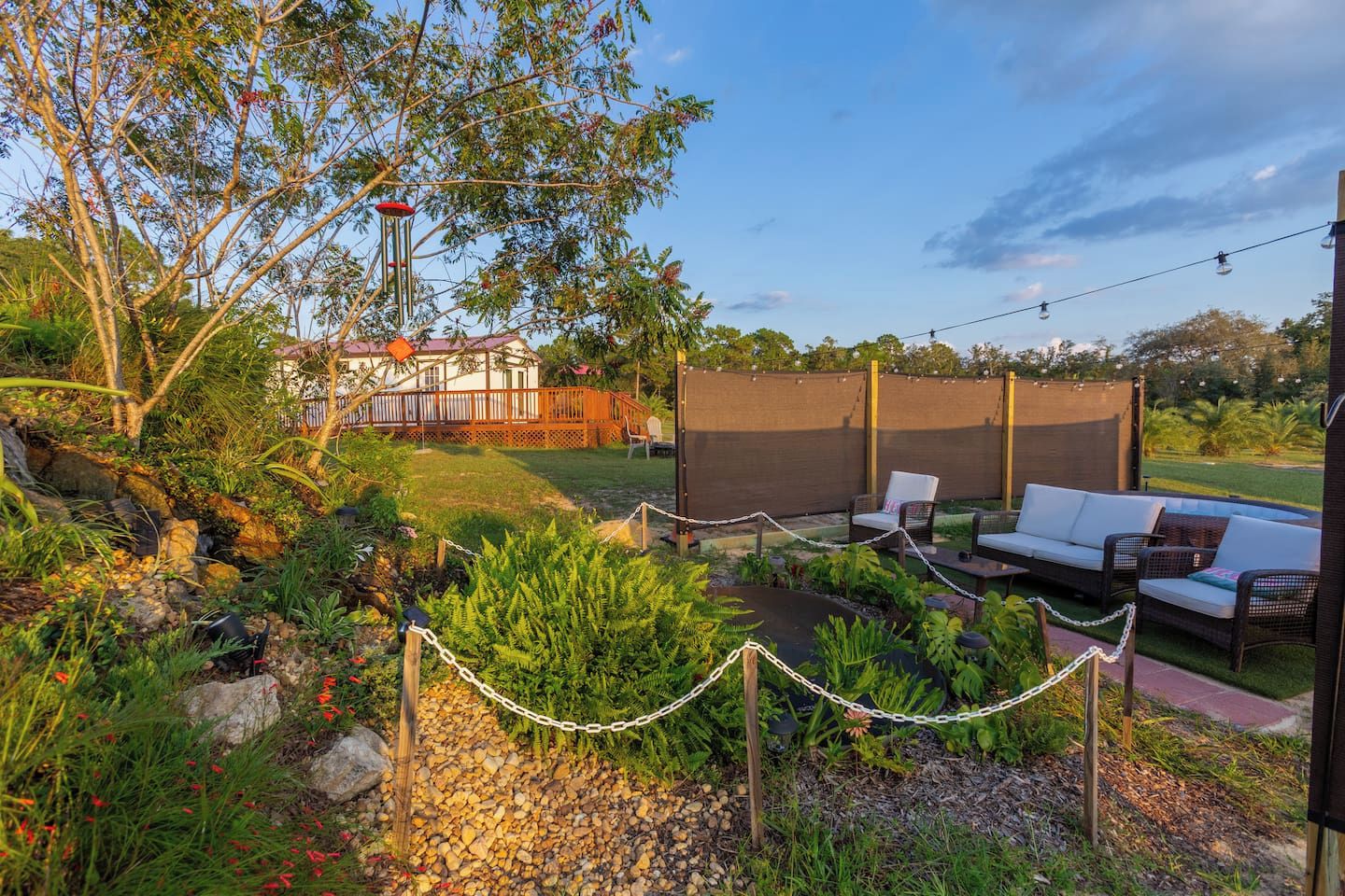 A backyard with a covered patio, outdoor seating, and a garden area.