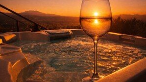 Ein Glas Weißwein in einer Hot Tub mit Sonnenuntergangblick.
