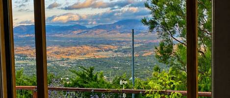 A balcony with a wooden deck, a hot tub, and a view of a mountainous landscape.