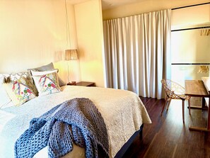 A hotel room with a bed, a desk, and a chair.