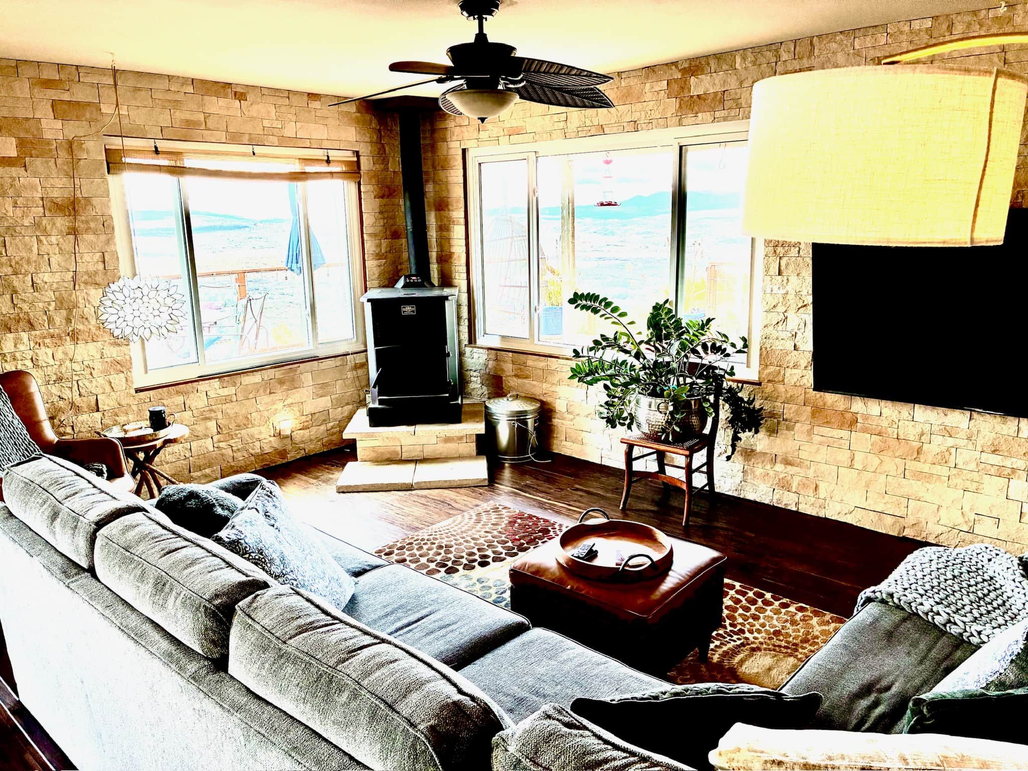 A living room with a stone wall, a fireplace, a sofa, a coffee table, and a large window with a view.