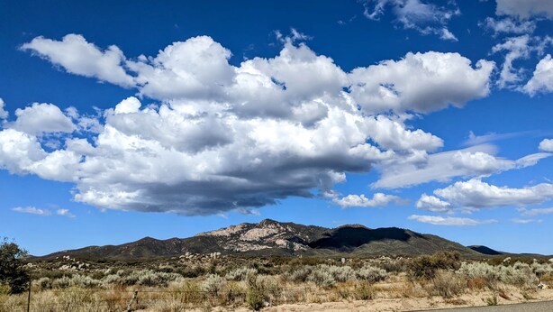 Eine gebirgige Landschaft mit kargen Pflanzen und blauem Himmel.