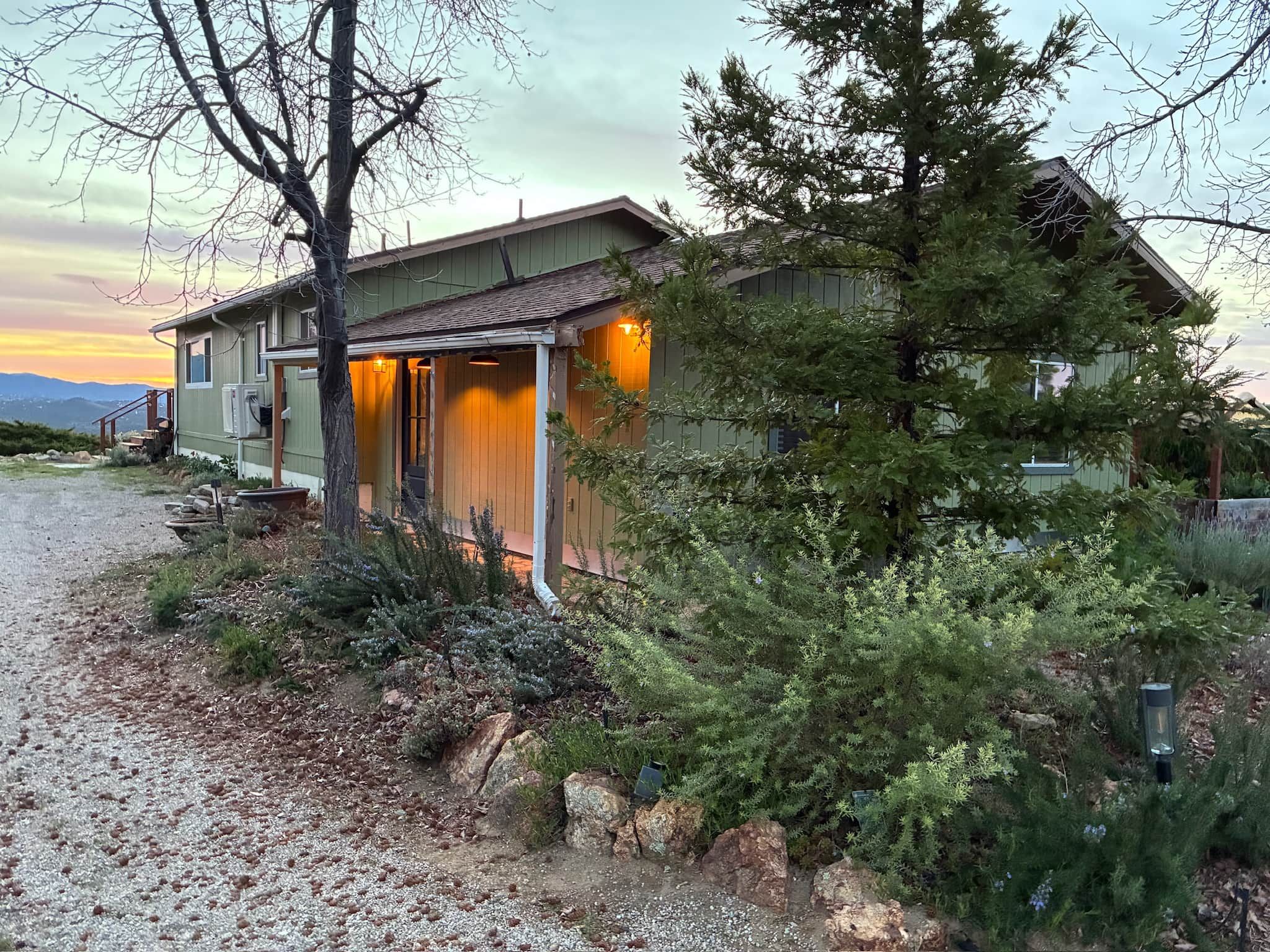 A two-story house with a covered porch and a gravel driveway.