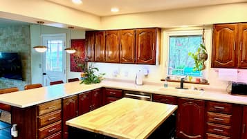 A modern kitchen with wooden cabinets, a central island, and a dining area.