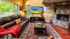 A living room with a leather sofa, a coffee table, a fireplace, and a TV on the wall.
