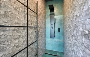 Een moderne douche met een strak, metalen bedieningspaneel en een opvallend, honingraatmotief op de wanden.