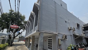 Un hotel con un letrero grande, unidades de aire acondicionado y un área de entrada cubierta.