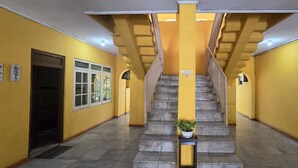 Una escalera en un pasillo con paredes amarillas y un cartel de 'No Smoking'.
