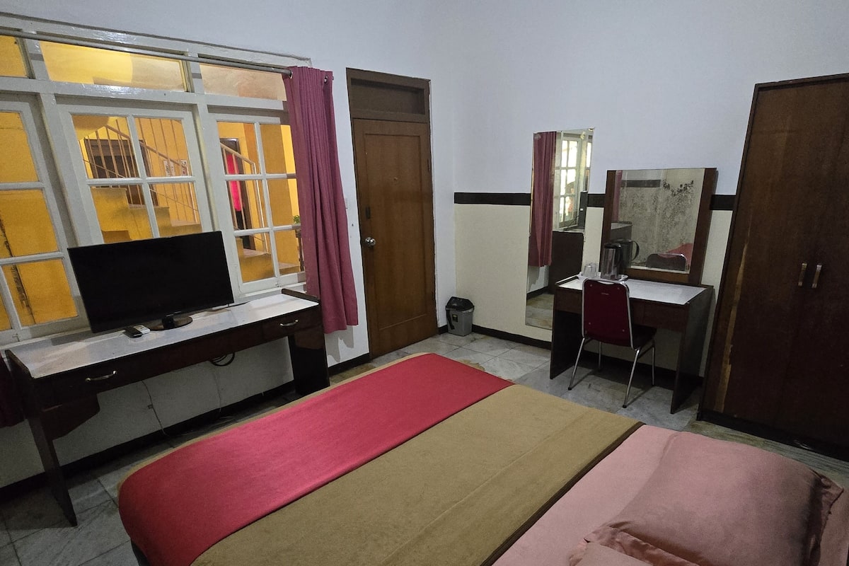 Une chambre d’hôtel comprenant un lit, un bureau avec un ordinateur, une télévision, un miroir et une armoire.