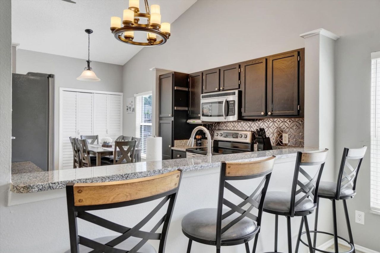 A modern kitchen with dark wood cabinets, a granite countertop, and a central island with bar stools.