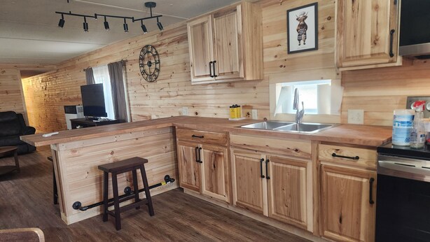 A modern kitchen with wooden cabinetry, a central island, a built-in oven, and a large window.