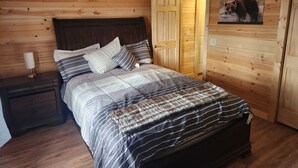 A wooden-paneled bedroom with a bed, nightstands, and a door.
