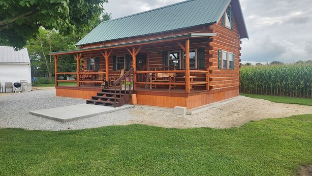 A rustic log cabin with a porch, a staircase, and a gravel driveway. - Charming 2-bedroom cabin in Carey with AC, WiFi (Carey)