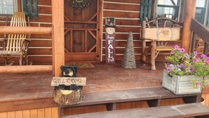 A rustic wooden cabin with a porch, a welcome sign, a bench, and a small Christmas tree. - Charming 2-bedroom cabin in Carey with AC, WiFi (Carey)