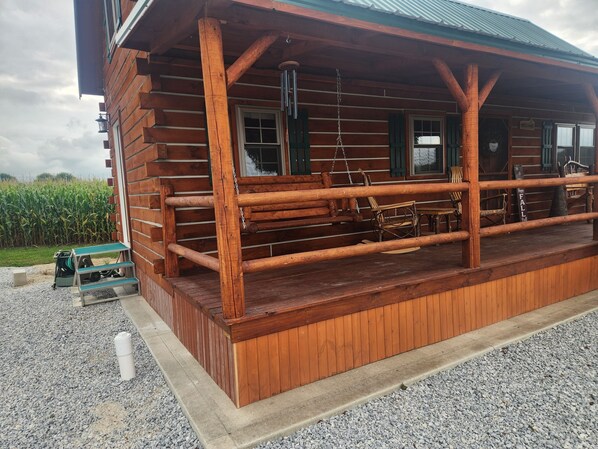 Una cabaña de madera con un porche, un cartel de bienvenida y un letrero que dice 'Otoño'.