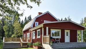 Une maison en bois rouge avec un porche, un escalier et un petit jardin.