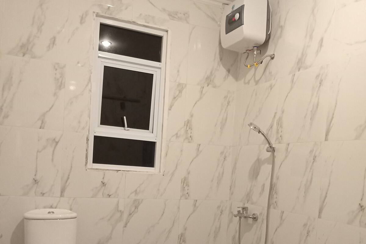 Un baño con inodoro, ducha y ventana.